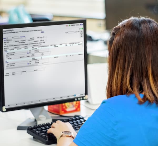 Woman in front of a computer typing on a keyboard, shot from behind