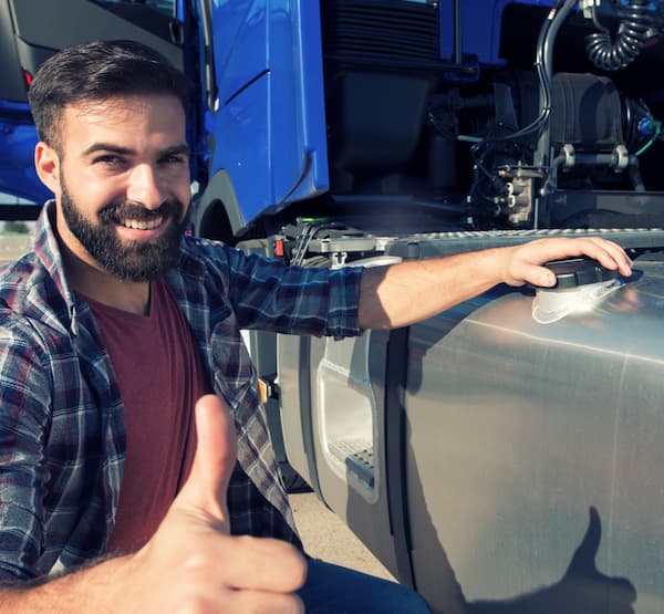 Man crouching in front of a truck smiliing and giving a thumbs up