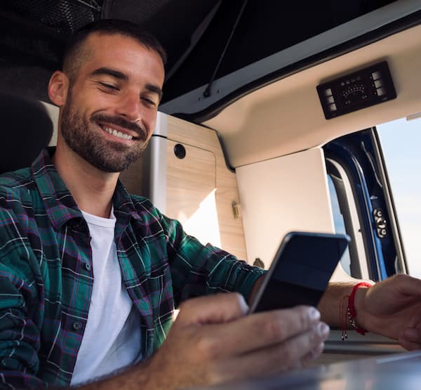 Truck driver in a truck smiling and looking down at his phone