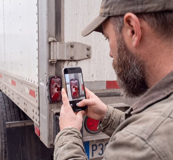 Someone taking a photo of a broken tail light on a truck